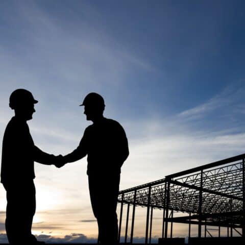 Construction two construction workers in hard hats shaking hands